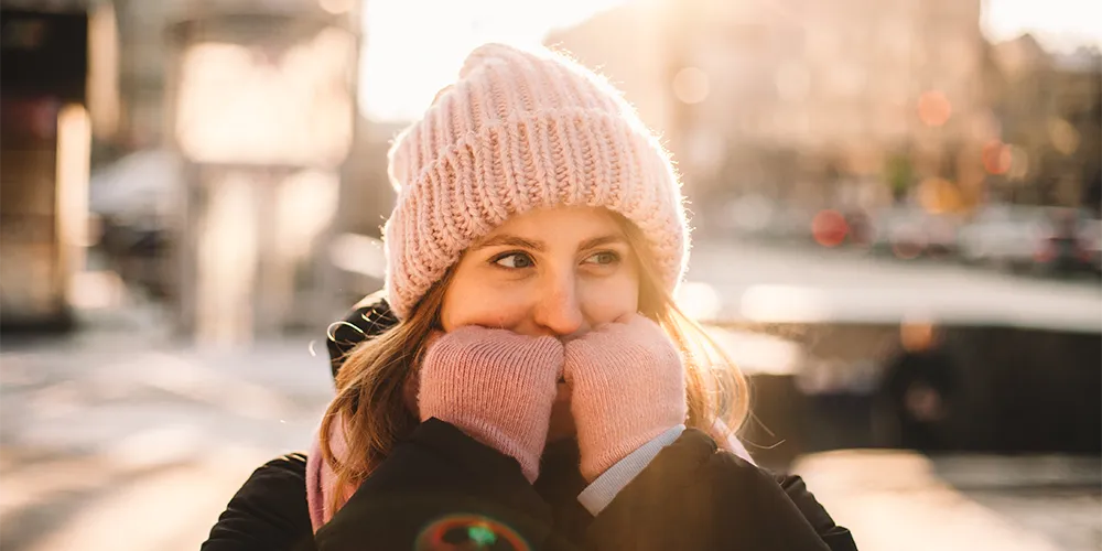 Änderungen im November / MLP Financify / Studentin mit Mütze und Handschuhen lächelt an einem kalten Herbsttag in der Stadt