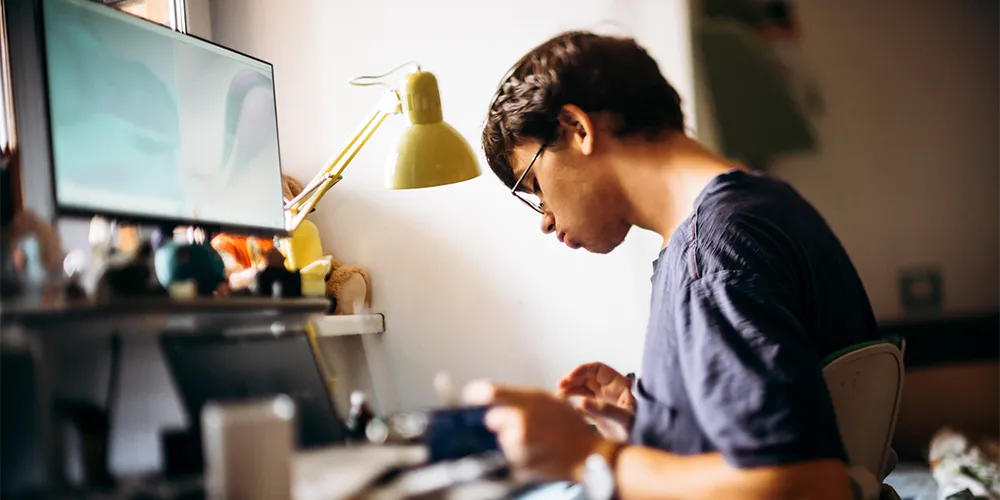 Fernstudium / MLP Financify / Student arbeitet am Laptop und lernt für sein Online-Studium im Home-Office.