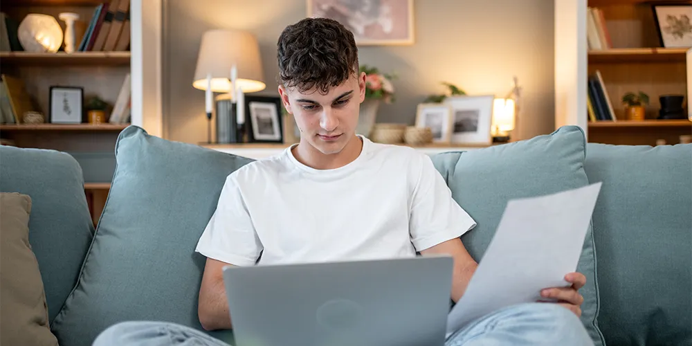 Welche Versicherungen brauche ich / MLP Financify / Student überprüft seine Versicherungsunterlagen am Laptop