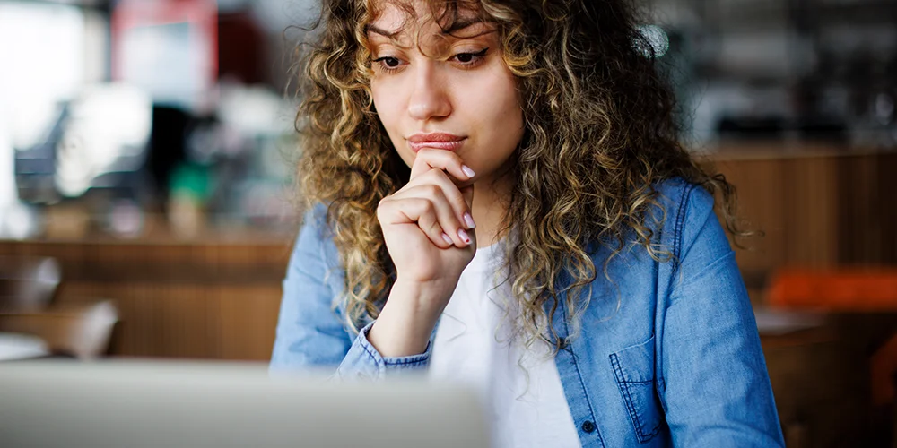Günstig Wohnen als Studierender – 5 Tipps für Wohn-Alternativen / MLP Financify / Studierende sitzt in Cafe an Laptop und recherchiert nach Wohnungsalternativen