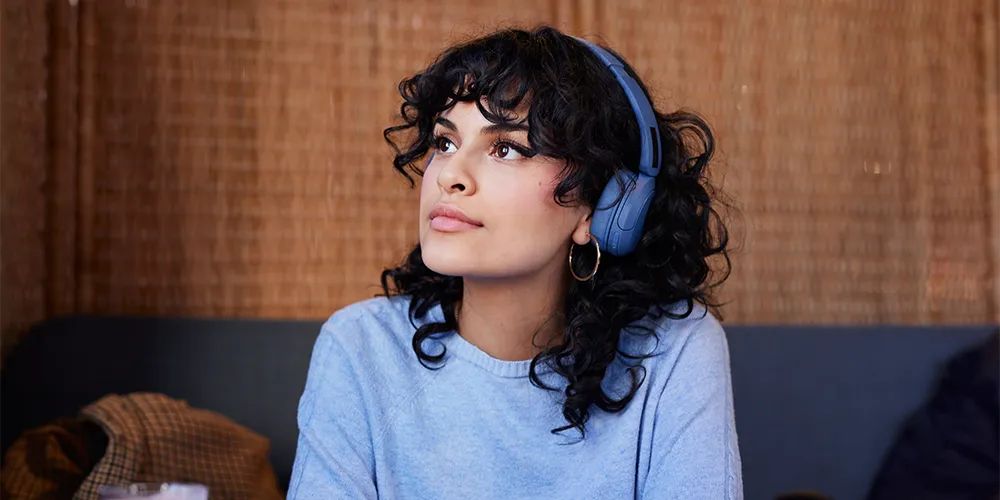 Hörbücher im Studium / MLP Financify / Studentin mit Kopfhörern hört konzentriert Hörbuch.