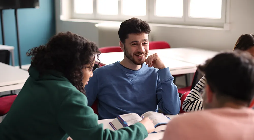 Introvertiert im Studium: Wie du dich trotzdem gut vernetzt und Freunde findest / MLP Financify / Introvertierter Student sitzt mit Freunden an einem Tisch und lernt