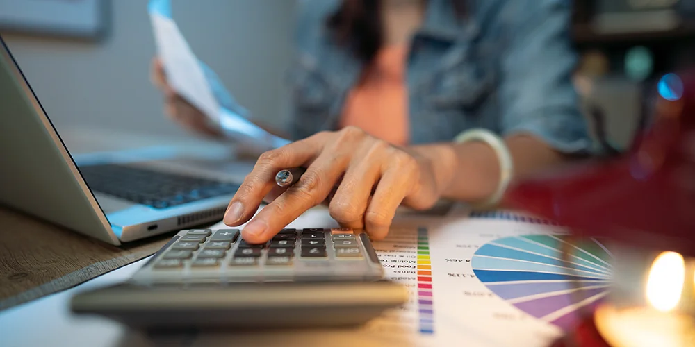 Kosten pro Semester: Beispiele für Studierende / MLP Financify / Studierende tippt Kosten in Taschenrechner ein und hält Rechnung in der Hand