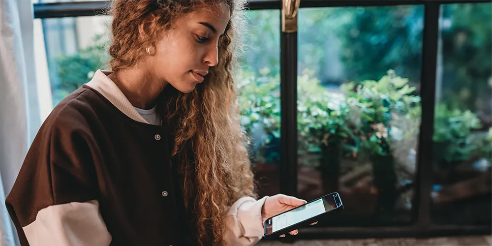 Microlearning / MLP Financify/ Studentin nutzt Microlearning App auf Smartphone für kurze Lerneinheiten im Alltag