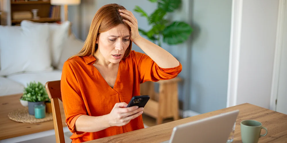 Was im Internet geht und was nicht: Umgang mit Fotos und Videos im Netz / MLP Financify / Studentin sitzt an Schreibtisch und schaut geschockt auf ihr Handy