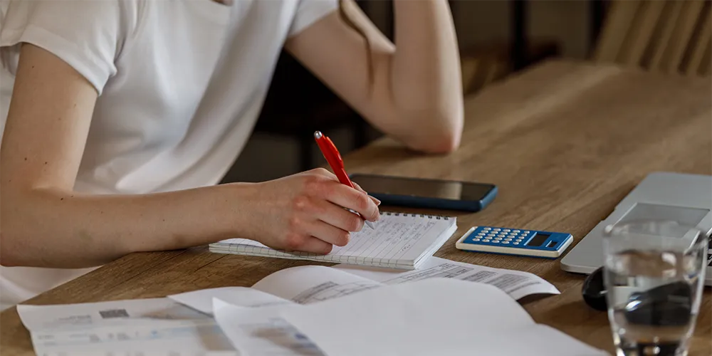 Ohne BAföG studieren / MLP Financify / Studentin sitzt an einem Tisch und rechnet verschiedene Studienfinanzierungen durch
