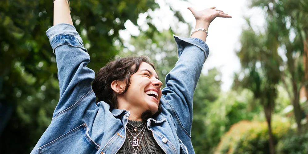 Jahresrückblick / MLP Financify / Junge Frau feiert Erfolge mit erhobenen Armen – Jahresrückblick und Ziele für 2026