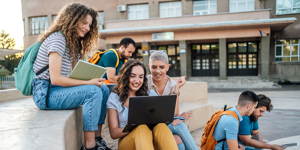 Studierende sitzen auf dem Campus