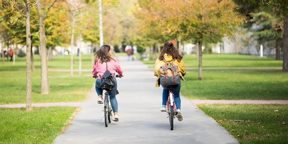 nachhaltige Aktivitaeten Semesterferien / MLP Financify / Studentinnen fahren Fahrrad auf dem Campus in den Semesterferien