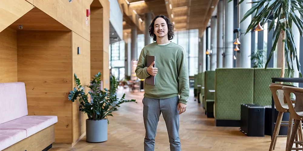 In 8 Schritten zum Startup / MLP Financify / Junger Gründer steht mit Laptop in modernem Büro
