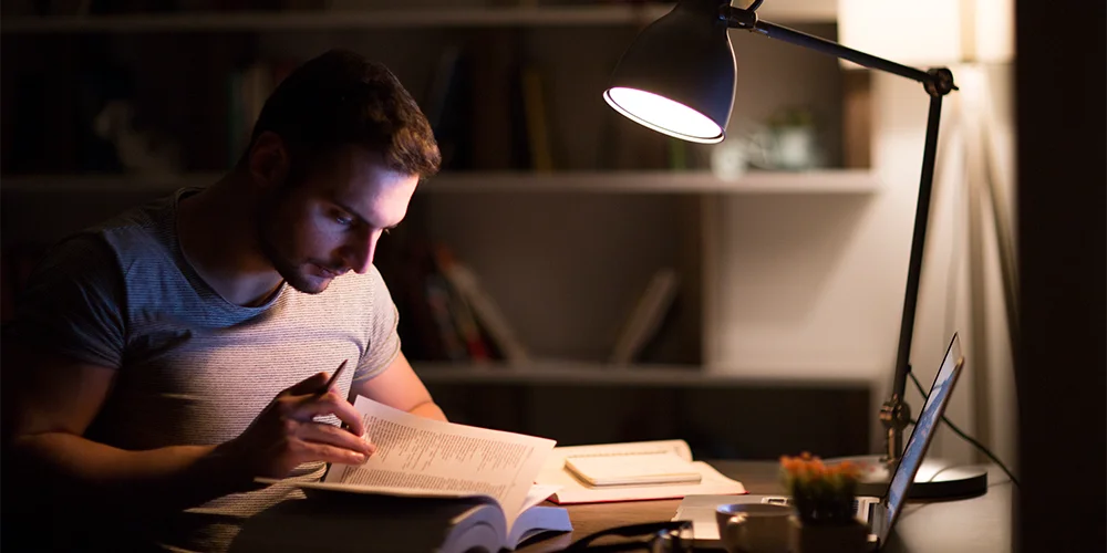 Strom sparen für Studierende / MLP Financify / Student am Schreibtisch mit kleiner Lampe