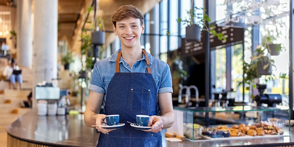 jobben in den Semesterferien / MLP Financify / Studentenjob in den Semesterferien: Kellner serviert Kaffee im Café.