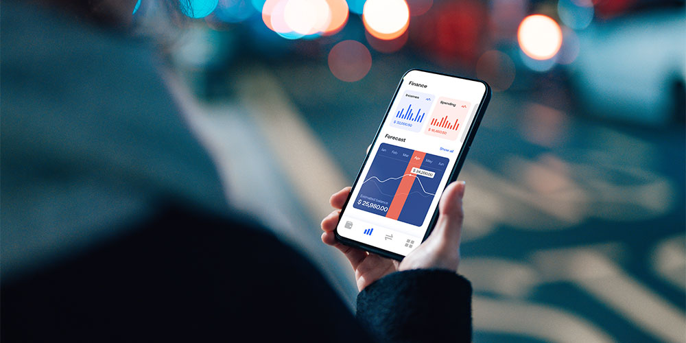 Sieben Regeln zum Vermögensaufbau / MLP Financify / Studentin hält Smartphone in der Hand das Finance Forecast zeigt.