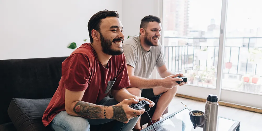 WG oder allein wohnen: Was passt besser zu dir? / MLP Financify / zwei Studenten spielen gemeinsam ein Videospiel