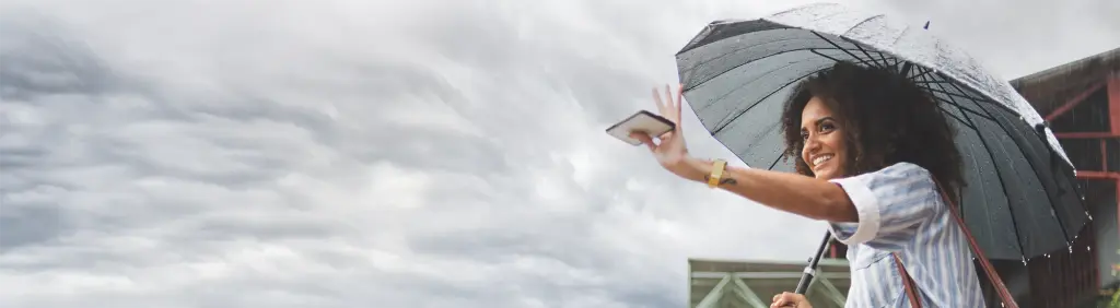 Absicherung im Ausland / MLP Financify / Studentin unter Regenschirm geschützt vom Regen